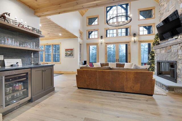 100 Morganite Way, Newry, ME 04261 - living room featuring wine cooler, bar with sink, a fireplace, high vaulted ceiling, and light wood-style flooring
