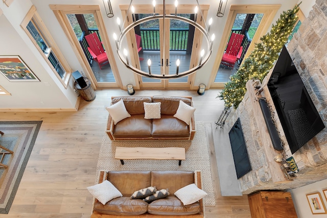 living area with an inviting chandelier, light hardwood / wood-style flooring, and a towering ceiling