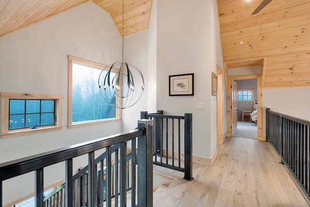 hallway featuring a notable chandelier, light hardwood / wood-style floors, wood ceiling, and high vaulted ceiling