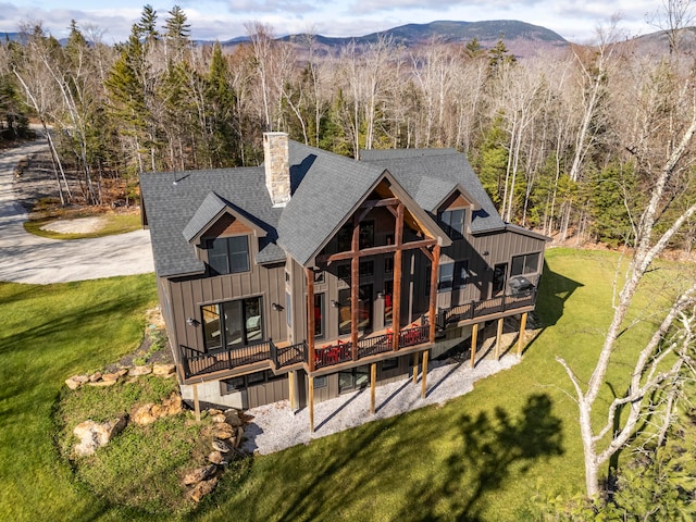 back of property with a deck with mountain view and a lawn