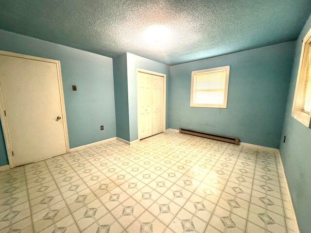 unfurnished bedroom featuring a baseboard heating unit, a textured ceiling, and a closet