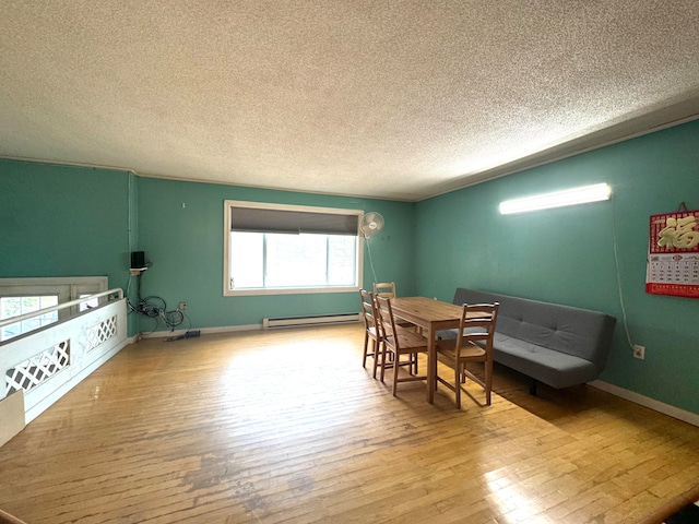 dining room with light hardwood / wood-style floors, a textured ceiling, and baseboard heating