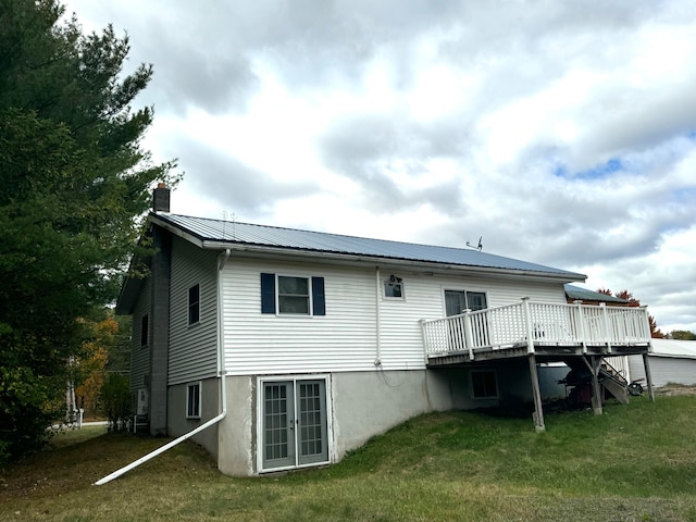 rear view of house featuring a deck and a lawn