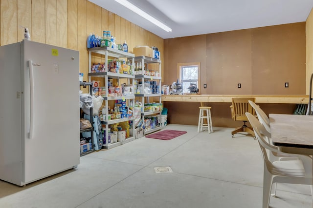 miscellaneous room featuring wooden walls and concrete floors