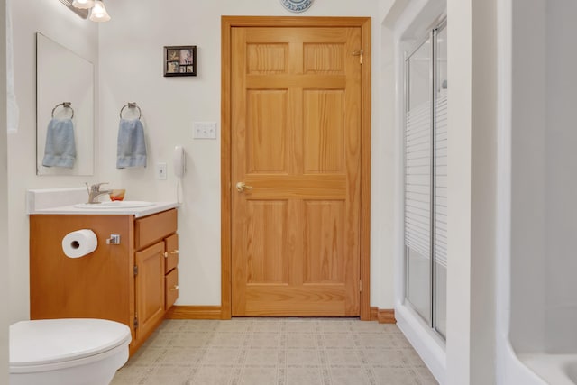 bathroom with a shower with door, vanity, and toilet