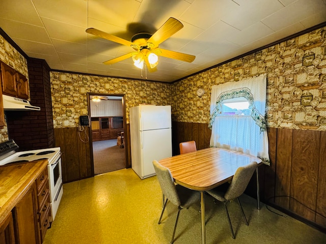 dining space featuring wooden walls and ceiling fan