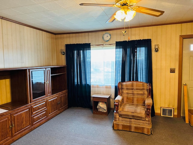 living area featuring ceiling fan, carpet, and ornamental molding