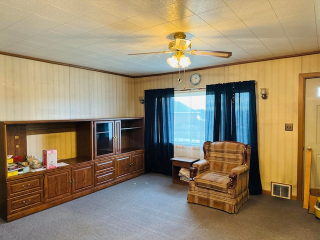 sitting room with ornamental molding, ceiling fan, and dark colored carpet