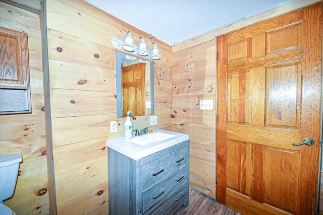 bathroom featuring vanity, toilet, wooden walls, and hardwood / wood-style floors