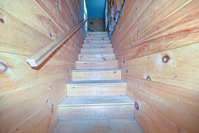 staircase featuring wood walls