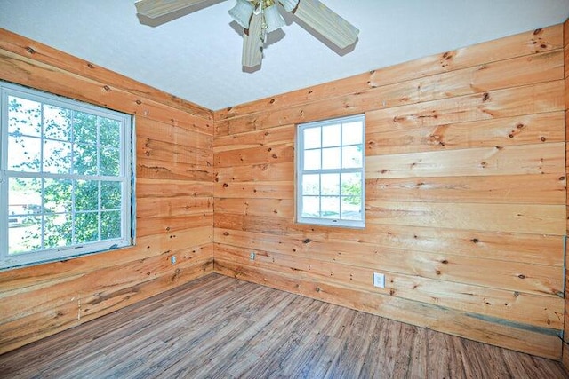 spare room with hardwood / wood-style flooring, a wealth of natural light, and wood walls