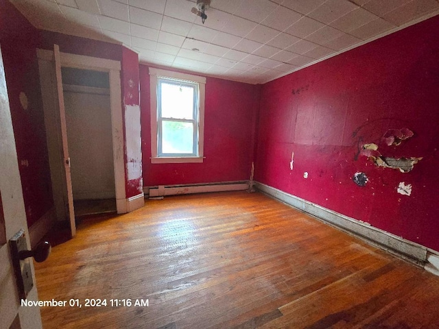 spare room featuring wood-type flooring and baseboard heating