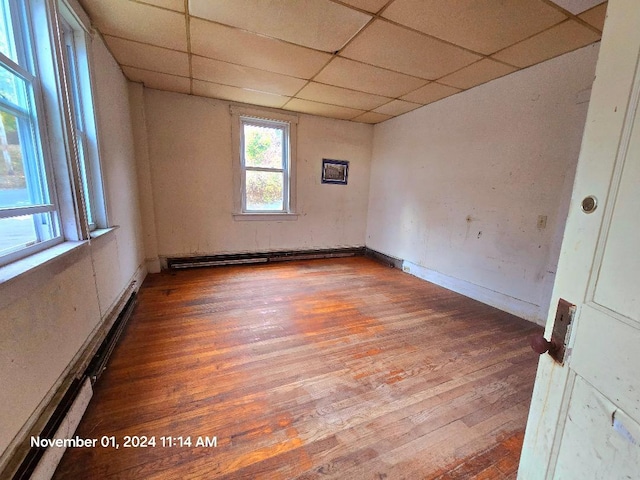 spare room featuring a baseboard heating unit, hardwood / wood-style flooring, and a paneled ceiling