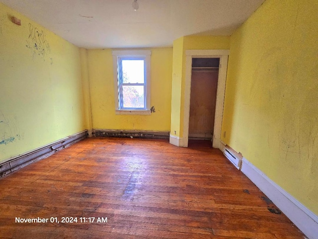 unfurnished bedroom featuring a closet, dark wood-type flooring, and a baseboard radiator