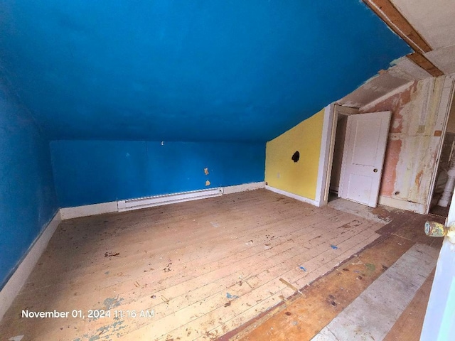 additional living space featuring wood-type flooring, a baseboard radiator, and vaulted ceiling