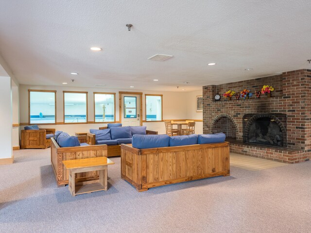 living room with a textured ceiling, a brick fireplace, and light colored carpet