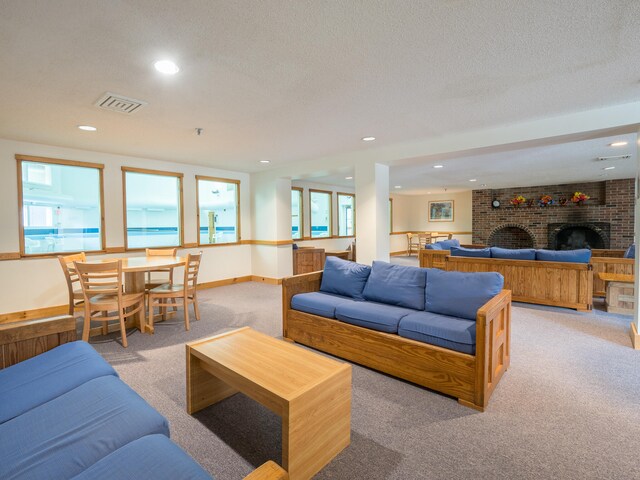 carpeted living room featuring a textured ceiling and a brick fireplace