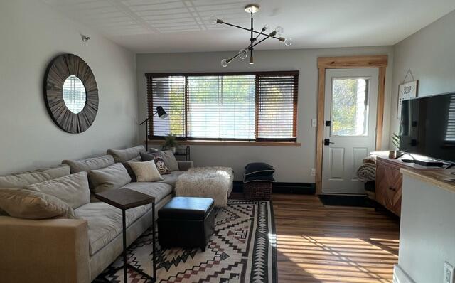 living room featuring wood-type flooring and an inviting chandelier