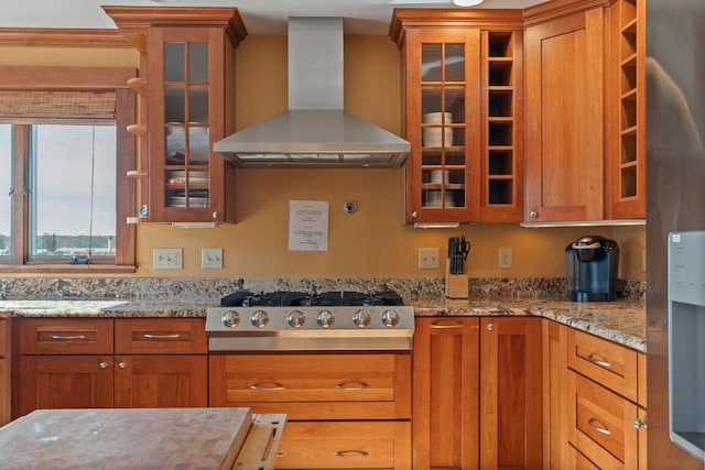 kitchen featuring wall chimney exhaust hood, stainless steel gas stovetop, and light stone countertops