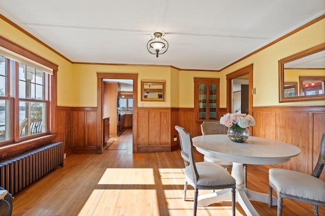 dining room with light wood-type flooring, radiator heating unit, and crown molding