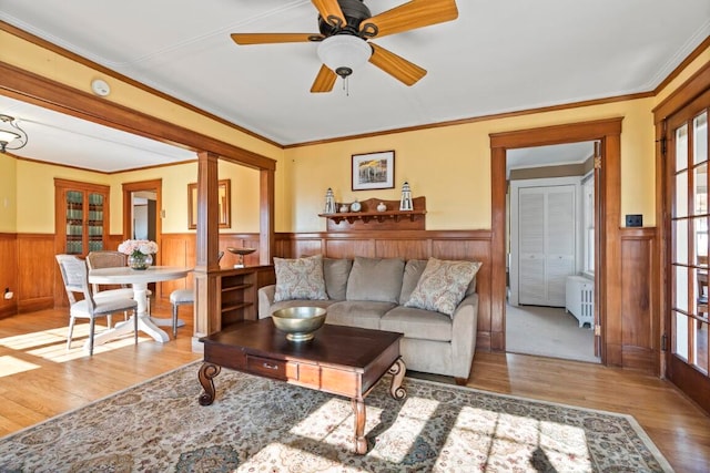 living room featuring ornate columns, light wood-type flooring, plenty of natural light, and ceiling fan