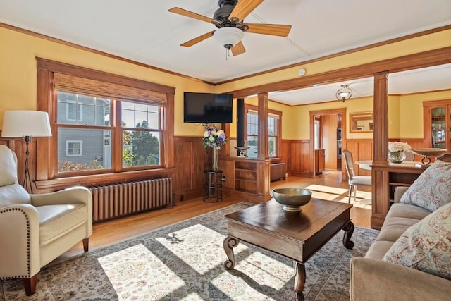 living room featuring ornate columns, radiator heating unit, ceiling fan, crown molding, and light hardwood / wood-style flooring