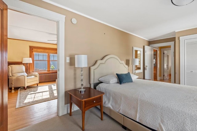 bedroom with radiator, hardwood / wood-style floors, a closet, and crown molding