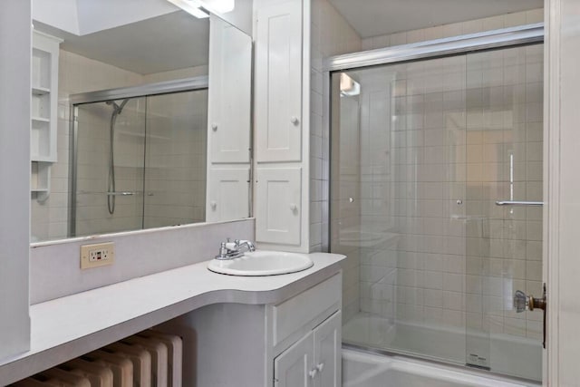 bathroom with vanity, radiator heating unit, and enclosed tub / shower combo