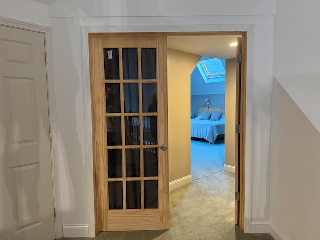 corridor featuring vaulted ceiling with skylight and carpet floors