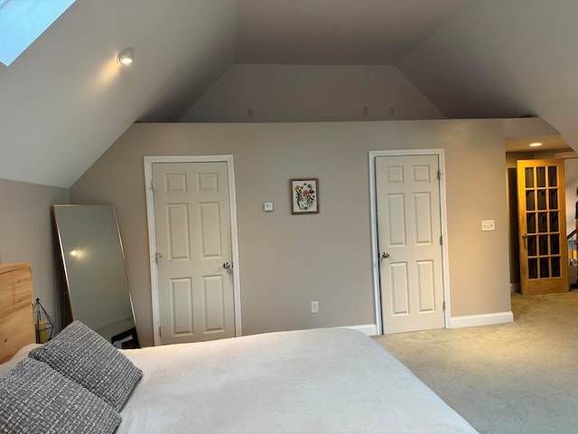 carpeted bedroom with vaulted ceiling with skylight