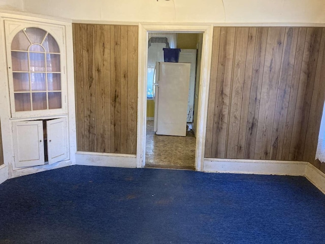 carpeted empty room with wooden walls