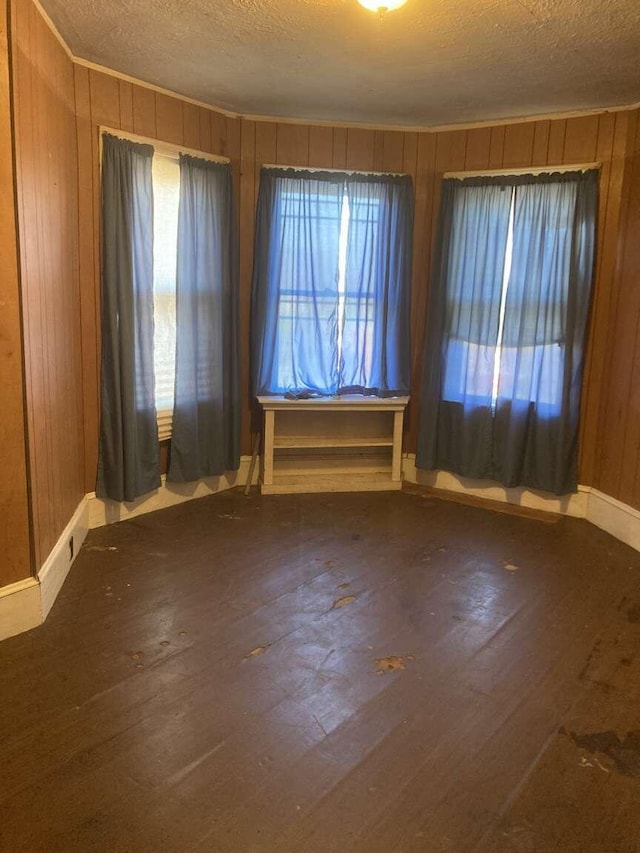 empty room with wood walls, wood-type flooring, and a textured ceiling