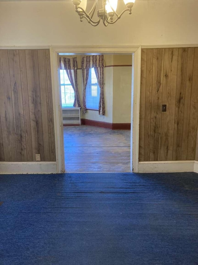 unfurnished room featuring an inviting chandelier, dark hardwood / wood-style floors, and wooden walls