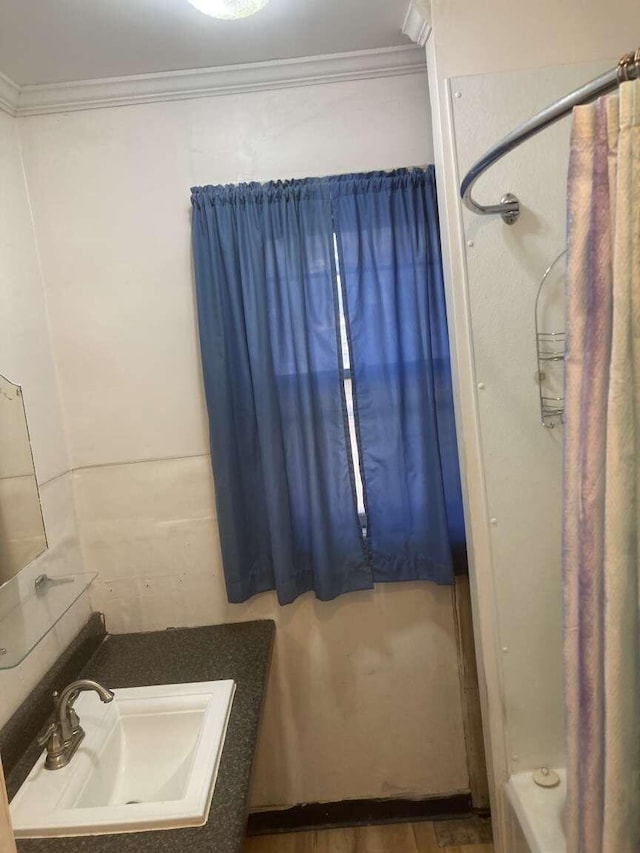 bathroom featuring sink, shower / bath combo with shower curtain, and crown molding