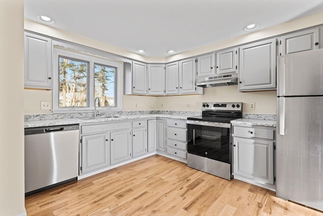 kitchen featuring light stone countertops, gray cabinetry, stainless steel appliances, sink, and light hardwood / wood-style floors