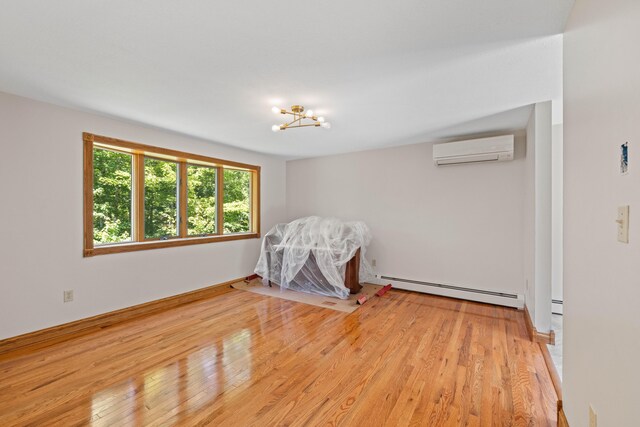221 Frost Rd, Lyman, ME 04002 - unfurnished bedroom with baseboard heating, a wall unit AC, wood finished floors, and a chandelier