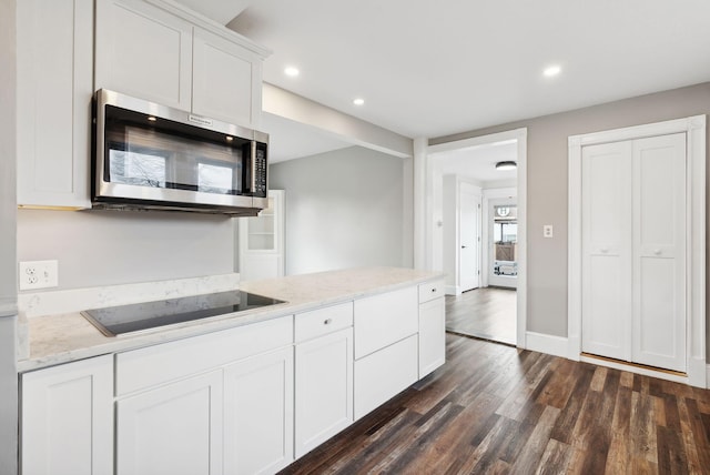 kitchen with white cabinets, dark hardwood / wood-style flooring, black electric cooktop, and light stone counters