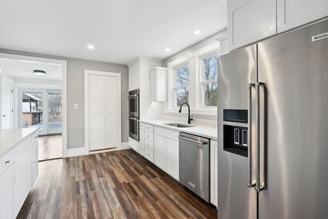 kitchen with stainless steel appliances, white cabinetry, dark wood-type flooring, and sink