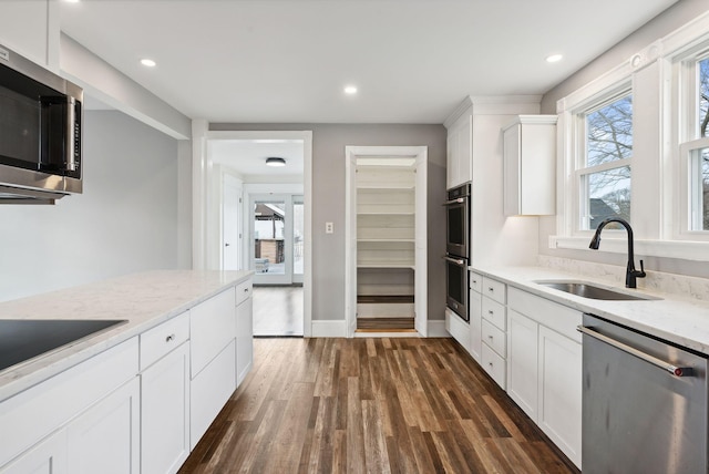 kitchen with light stone countertops, sink, dark wood-type flooring, white cabinets, and appliances with stainless steel finishes