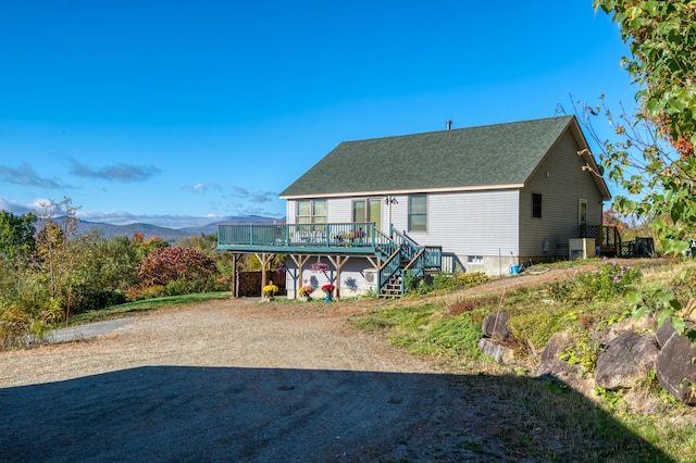 58 Wheeler Hill Rd, Phillips, ME 04966 - back of property with a deck with mountain view, central AC, stairs, and roof with shingles