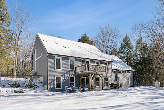 snow covered property featuring a chimney, fence, and a balcony