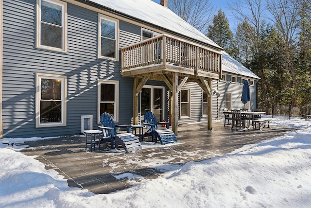 snow covered back of property featuring fence, a patio, and a balcony