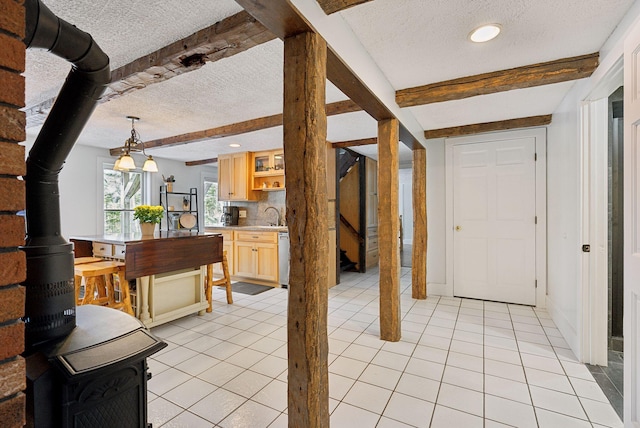 entrance foyer featuring a wood stove, light tile patterned flooring, beam ceiling, a textured ceiling, and stairs