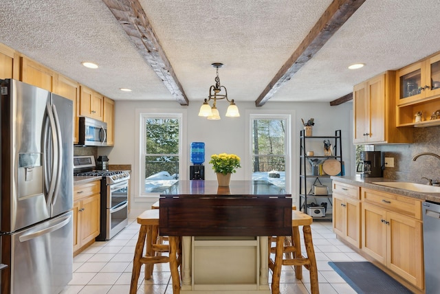 kitchen with tasteful backsplash, a textured ceiling, a sink, light tile patterned floors, and stainless steel appliances