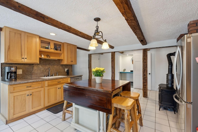 kitchen featuring beam ceiling, freestanding refrigerator, a sink, and light tile patterned floors