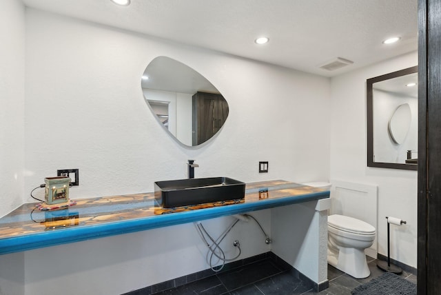 half bath with recessed lighting, visible vents, toilet, and a sink