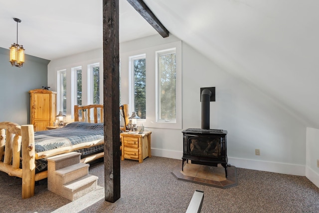 bedroom with carpet floors, a wood stove, vaulted ceiling with beams, and baseboards