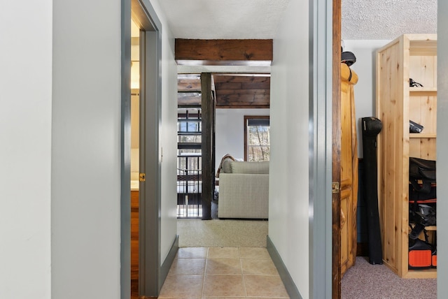 hall with baseboards, light carpet, and light tile patterned floors