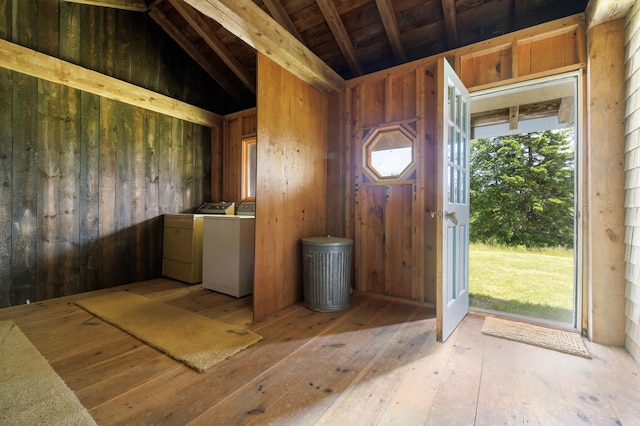 foyer entrance with vaulted ceiling with beams, wood walls, and washing machine and dryer