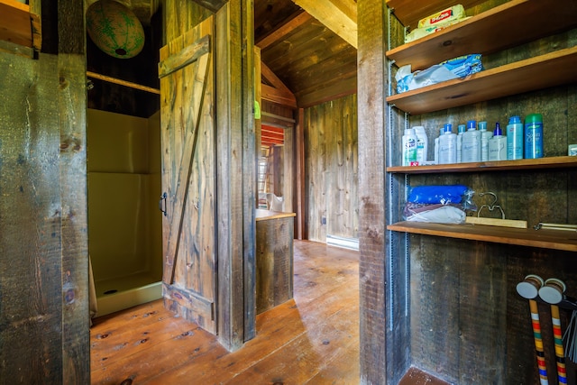 interior space featuring lofted ceiling, wooden walls, and hardwood / wood-style flooring